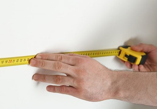 Man measuring wall with tape measure